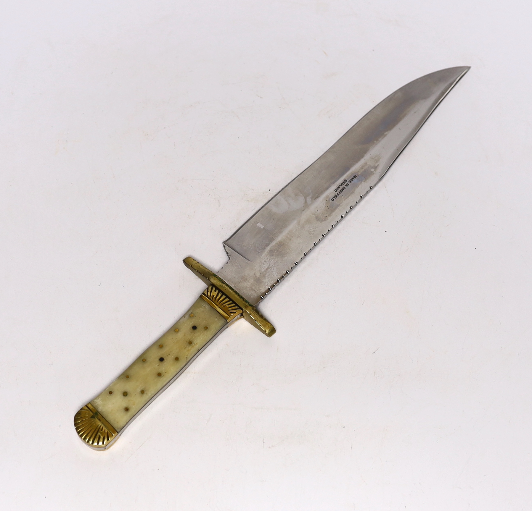 A Bowie knife with clip point blade, unsharpened false edge and decorative filework, marked made in Sheffield England, with bone grip, decorated with brass pins, brass guard and pommel, blade 25.5cm